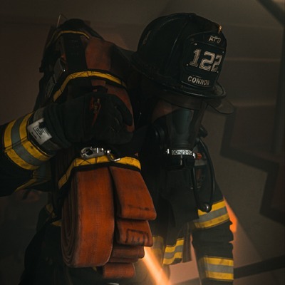 Firefighter carrying a hose up a smokey staircase for a recruitment video shoot